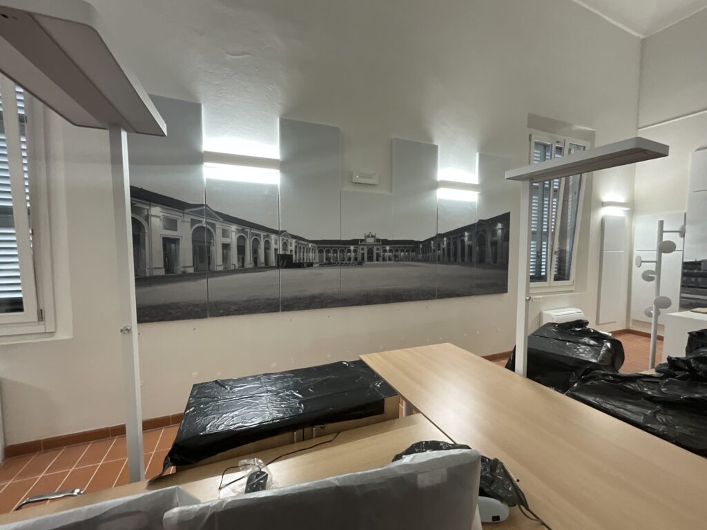 Parete del locale del Comune di Lugo con pannelli fonoassorbenti bianchi e stampe fotografiche in bianco e nero dei monumenti locali realizzati da Studio T